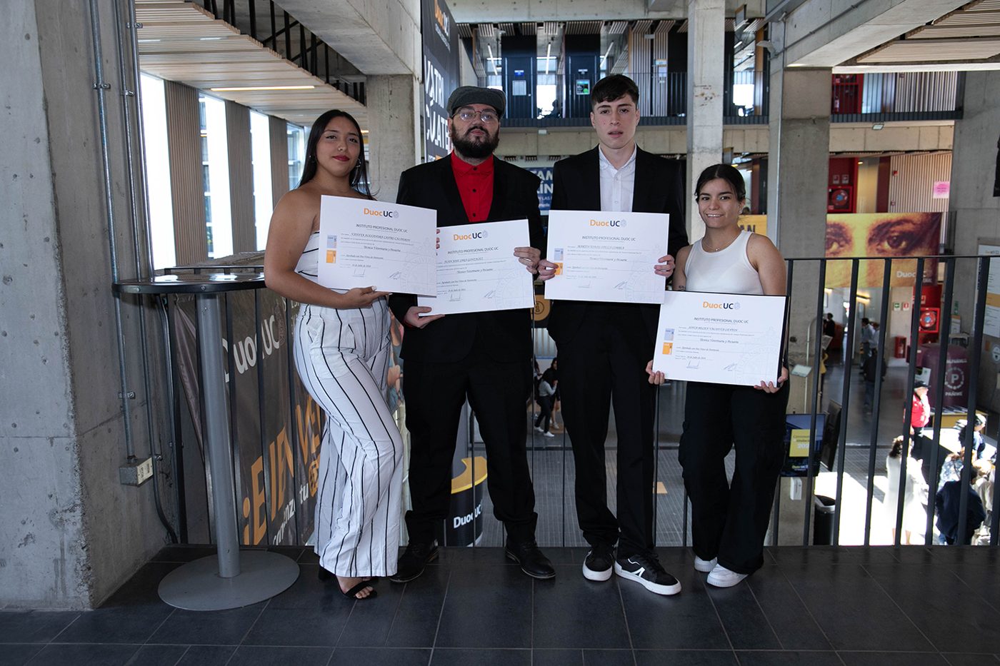 Grupo de cuatro titulados mostrando sus diplomas